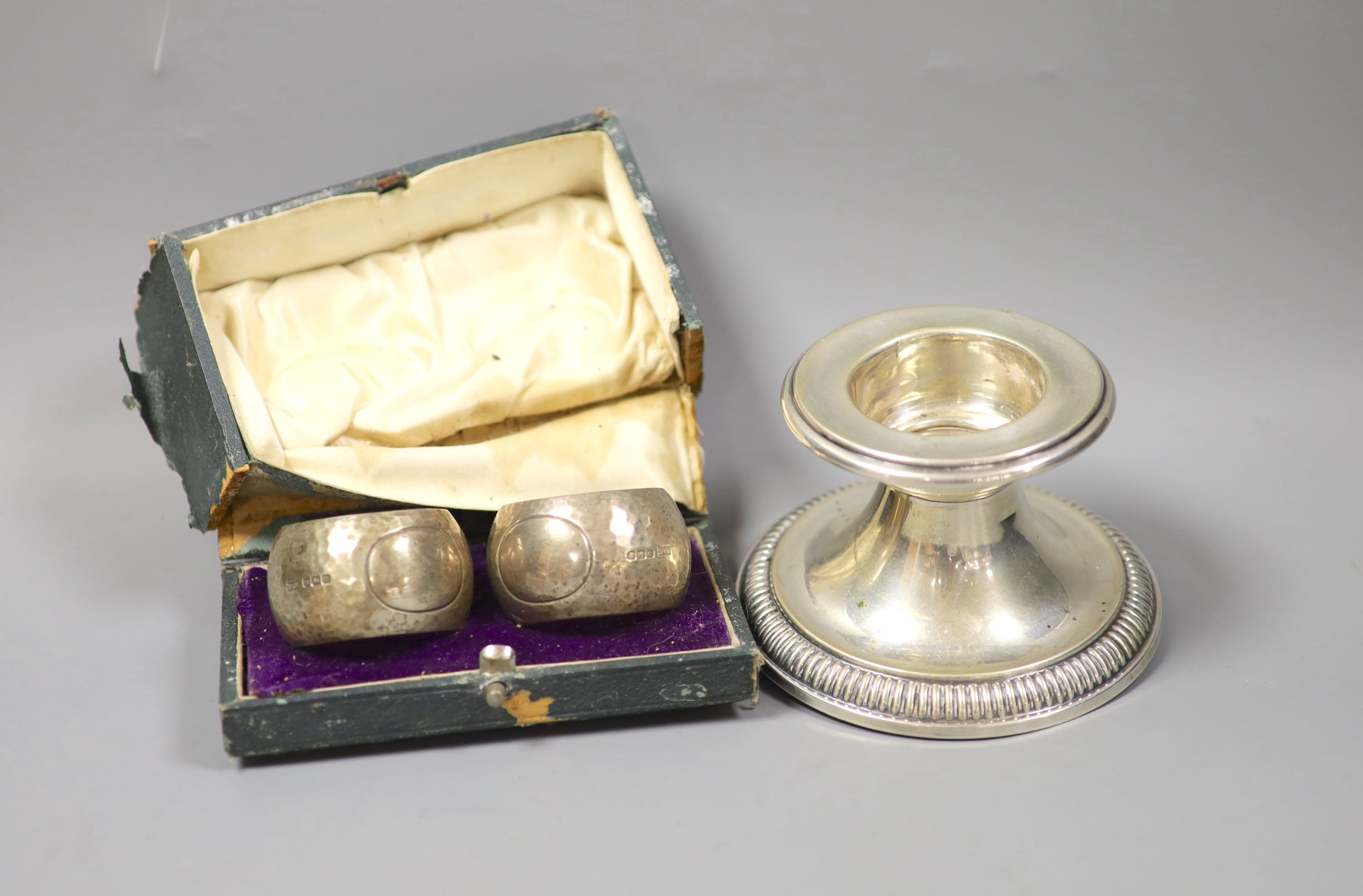 A German white metal dwarf candlestick and a cased pair of silver napkin rings by Walker & Hall.